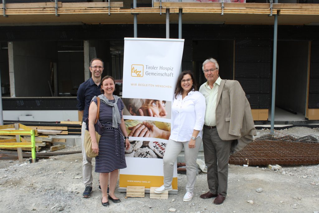 Zwei Frauen und zwei Männer stehen vor einem Haus, das gerade gebaut wird.