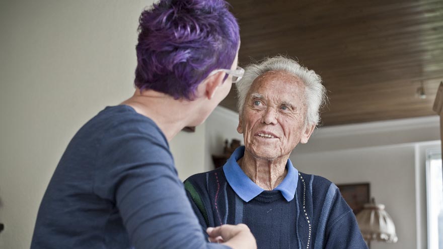 Eine Frau mit kurzen Haaren spricht mit einem älteren Mann, der lächelt