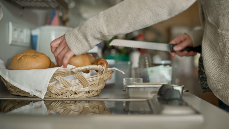 Das Bild zeigt einen Brötchenkorb und eine Person, die daraus ein Brötchen entnimmt