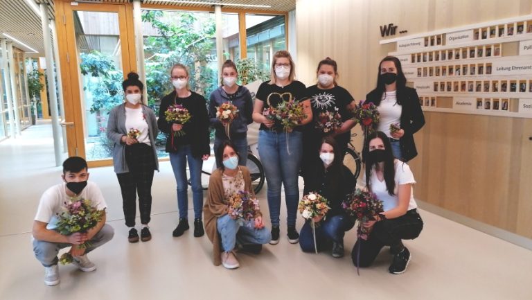 Eine Gruppe mit neun Schülerinnen der Tiroler Fachberufsschule für Garten, Raum und Mode mit Blumensträußen für das Hospiz