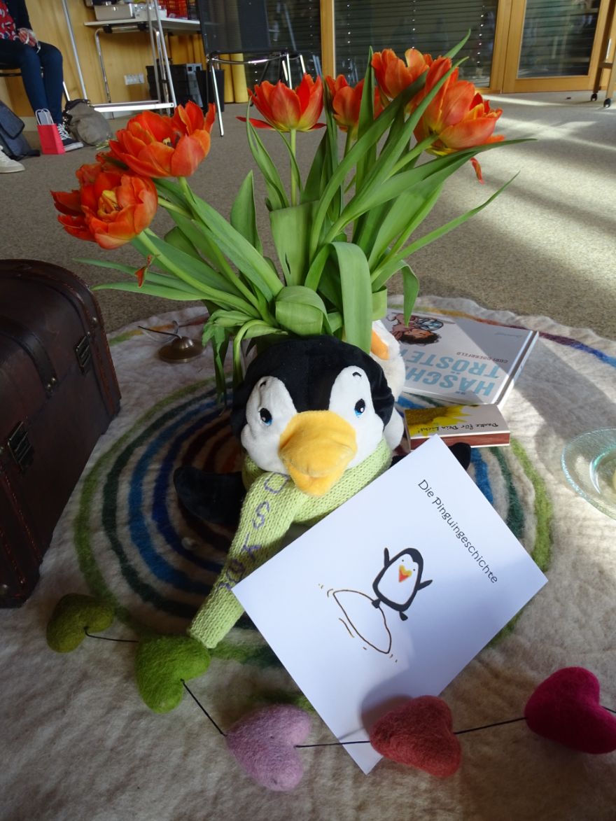 Blumen, Stoffpinguin und Karte "Die Pinguingeschichte"