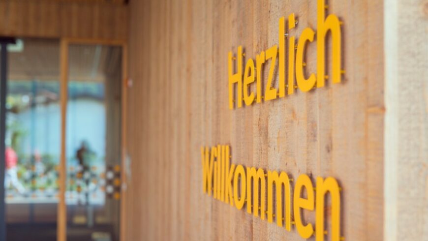 Der Schriftzug "Herzlich willkommen" auf der Holzwand vor dem Eingang ins Hospizhaus