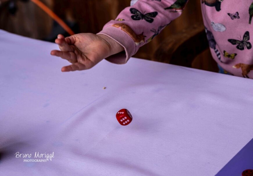 Das Mädchen lässt einen Würfel aus der Hand fallen