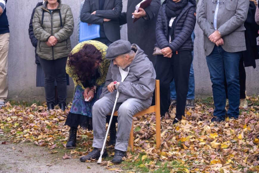 Projektmitarbeiterin Elisabeth Draxl neigt sich einem älteren Mann der auf einem Stuhl sitzt zu