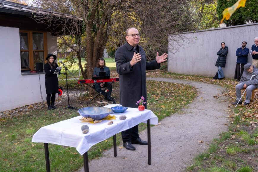 Hermann Glettler mit ausgebreiteten ARmen neben dem Tisch, der als Altar dient