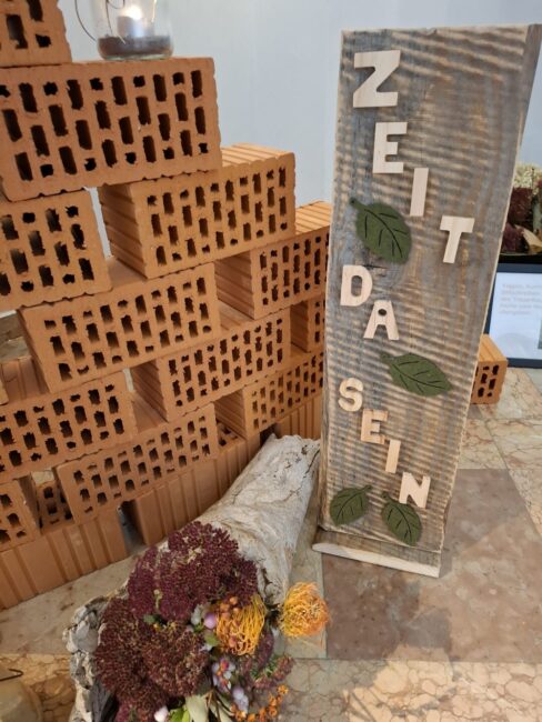 Die Klagemauer aus Ziegeln und ein Ständer mit der Aufschrift Zeit und Da Sein