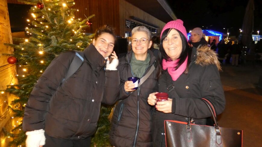 Beim Glühwein drei lachende Mitarbeiterinnen