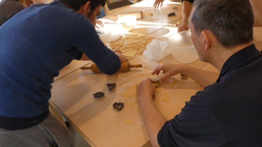 Ein Kind rollt den Teig aus, ein Patient sticht ein Keks mit der Form aus