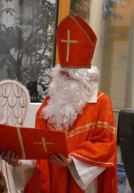 Der Nikolaus hält eine rote Mappe in der Hand