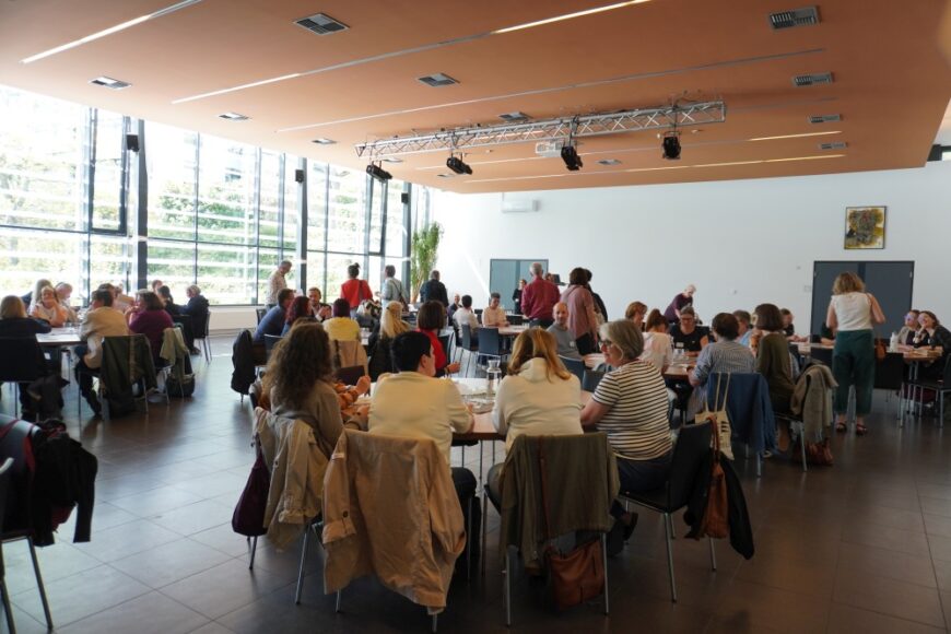 Teilnehmer*innen am Palliativtag auf Tische verteilt.