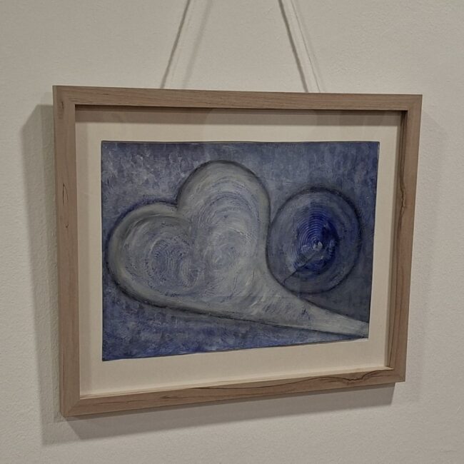 Abstraktes blau-graues Gemälde mit einer geschwungenen Herzform und einem kreisförmigen Muster in einem hellen Holzrahmen an einer weißen Wand.