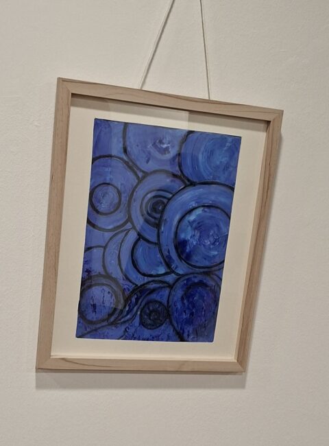 Abstraktes blaues Gemälde mit überlappenden Kreis- und Spiralformen in einem hellen Holzrahmen an einer weißen Wand.