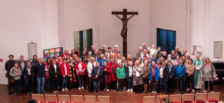 Große Gruppenaufnahme der Mitwirkenden und Gottesdienstbesuchenden vor dem Altar und dem großen Kruzifix in der Kirche.